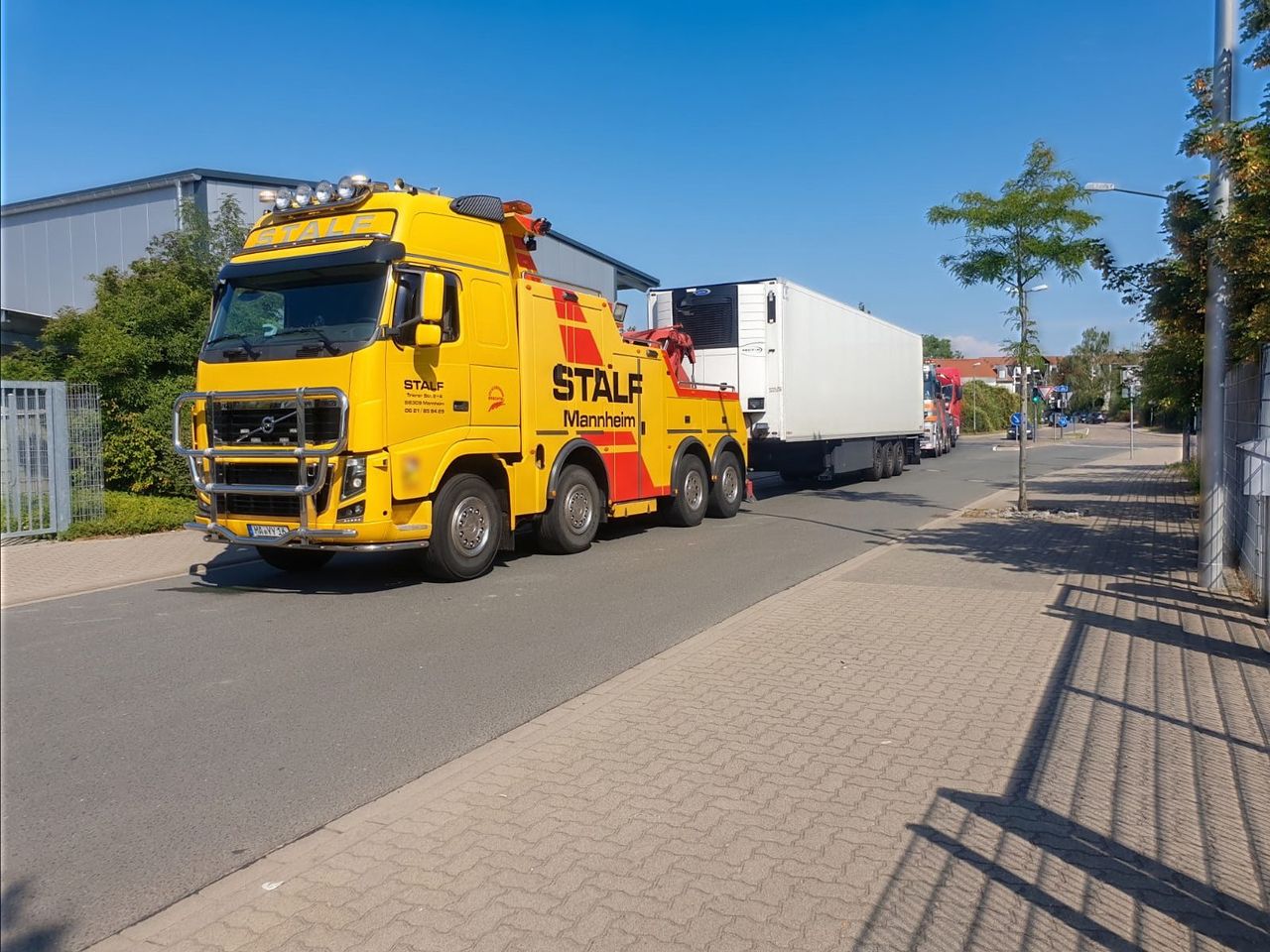 Gelbes Bergefahrzeug der STALF KG mit Sattelzug auf einer Straße in Mannheim
